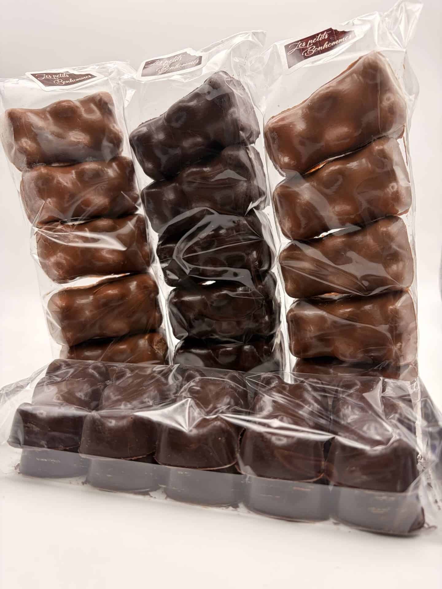 Assortiment d'oursons guimauve en sachets, enrobés de chocolat noir, chocolat au lait et chocolat blanc, accompagné de guimauves enrobées de chocolat noir.